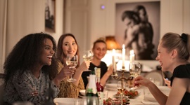 Een foto van mooie buitenlandse vrouwen die wijn drinken en gezellig samenzijn terwijl ze aan een chique eettafel zitten