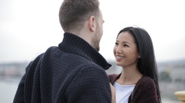 Een foto van een buitenlandse man en een Aziatische vrouw die elkaar vrolijk in de ogen kijken