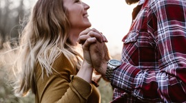 Een foto van een man en een vrouw die elkaar vrolijk aankijken terwijl ze elkaars hand vasthouden